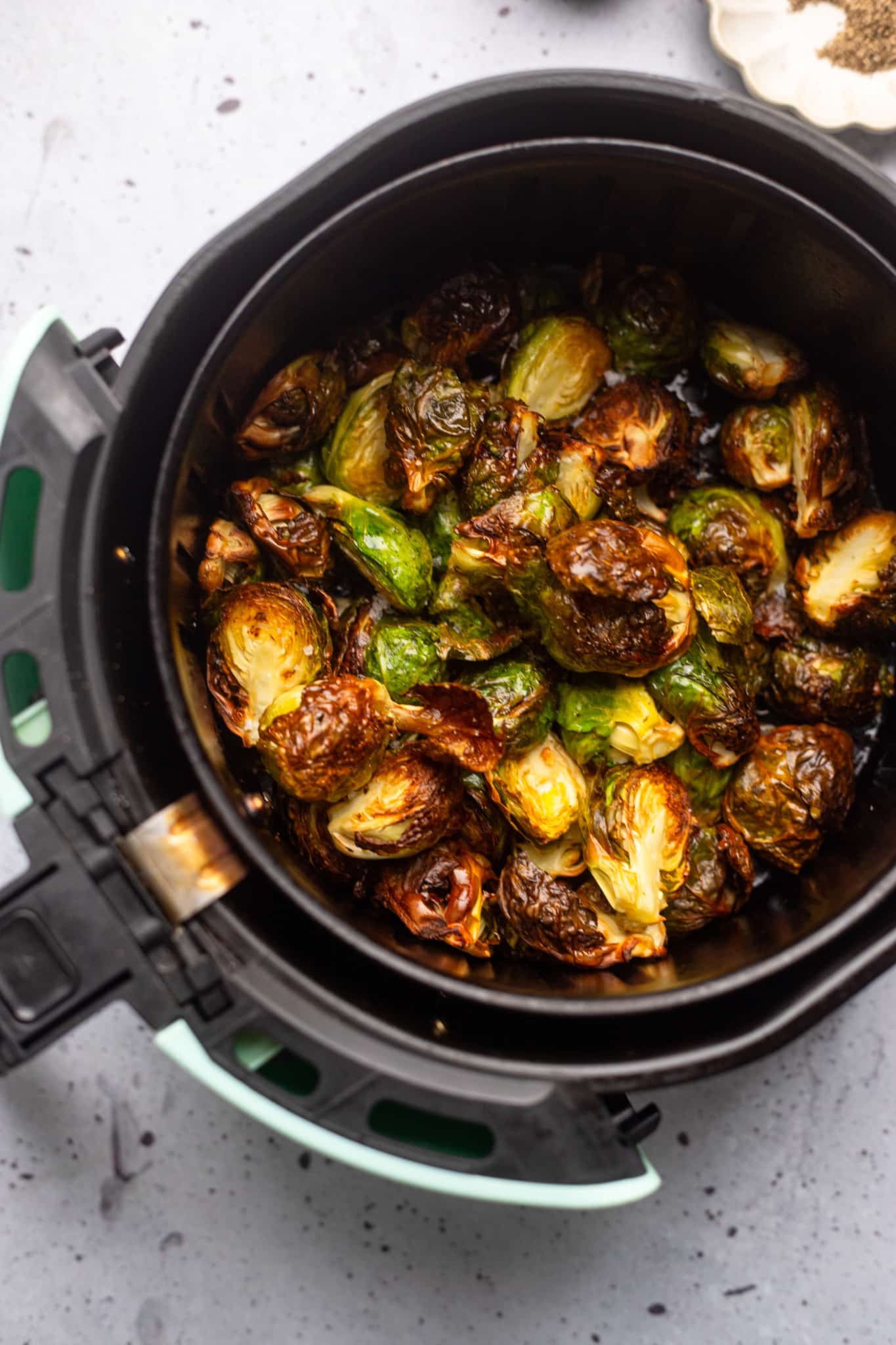 cooked brussels sprouts in an air fryer basket.