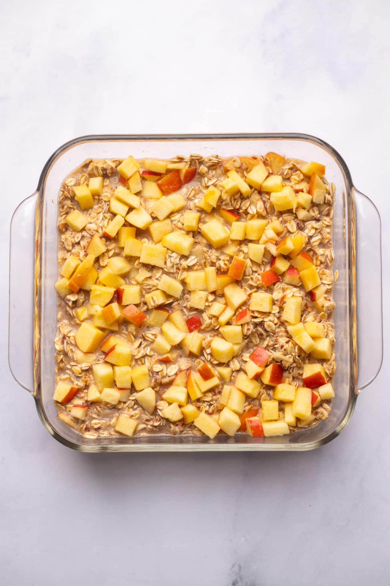 unbaked apple baked oatmeal in a glass baking dish.