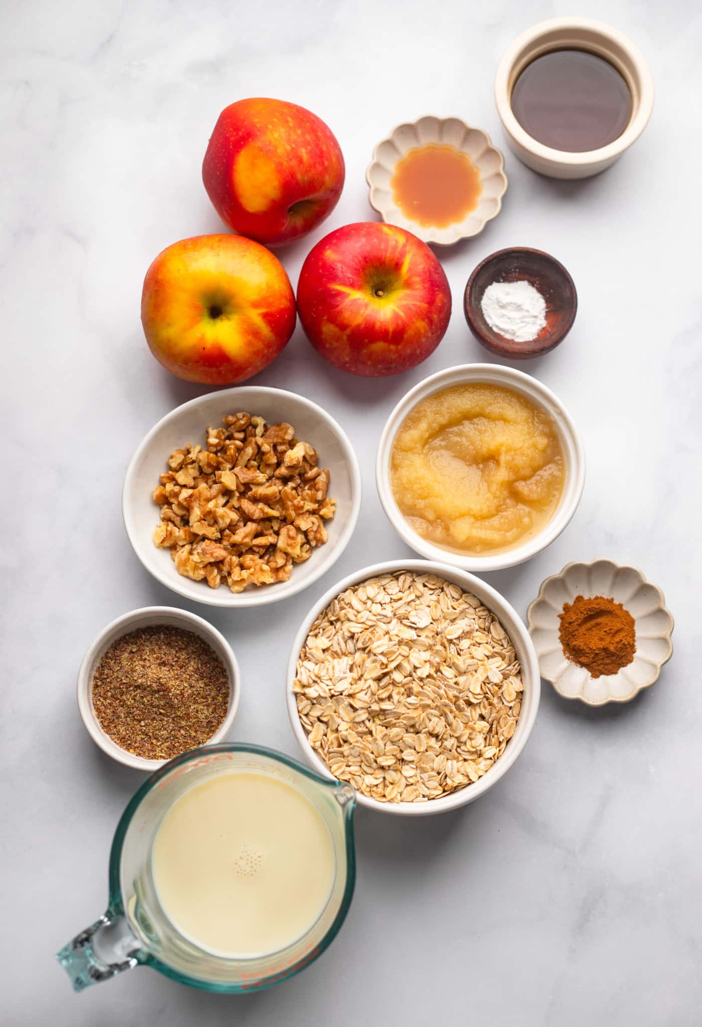 ingredients for apple baked oatmeal in individual white bowls.