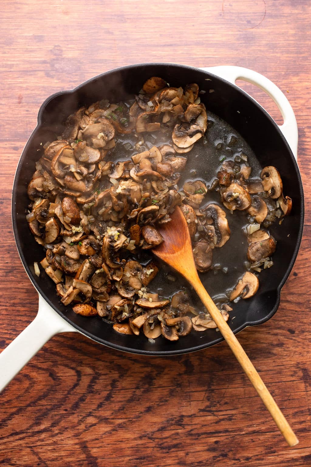 cooking sliced mushrooms in a black skillet.