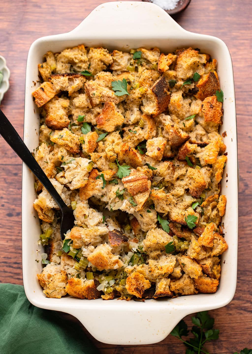 stuffing in a white casserole dish with black spoon in it