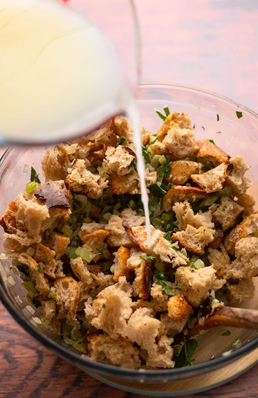 mixture being poured over bread cubes in bowl