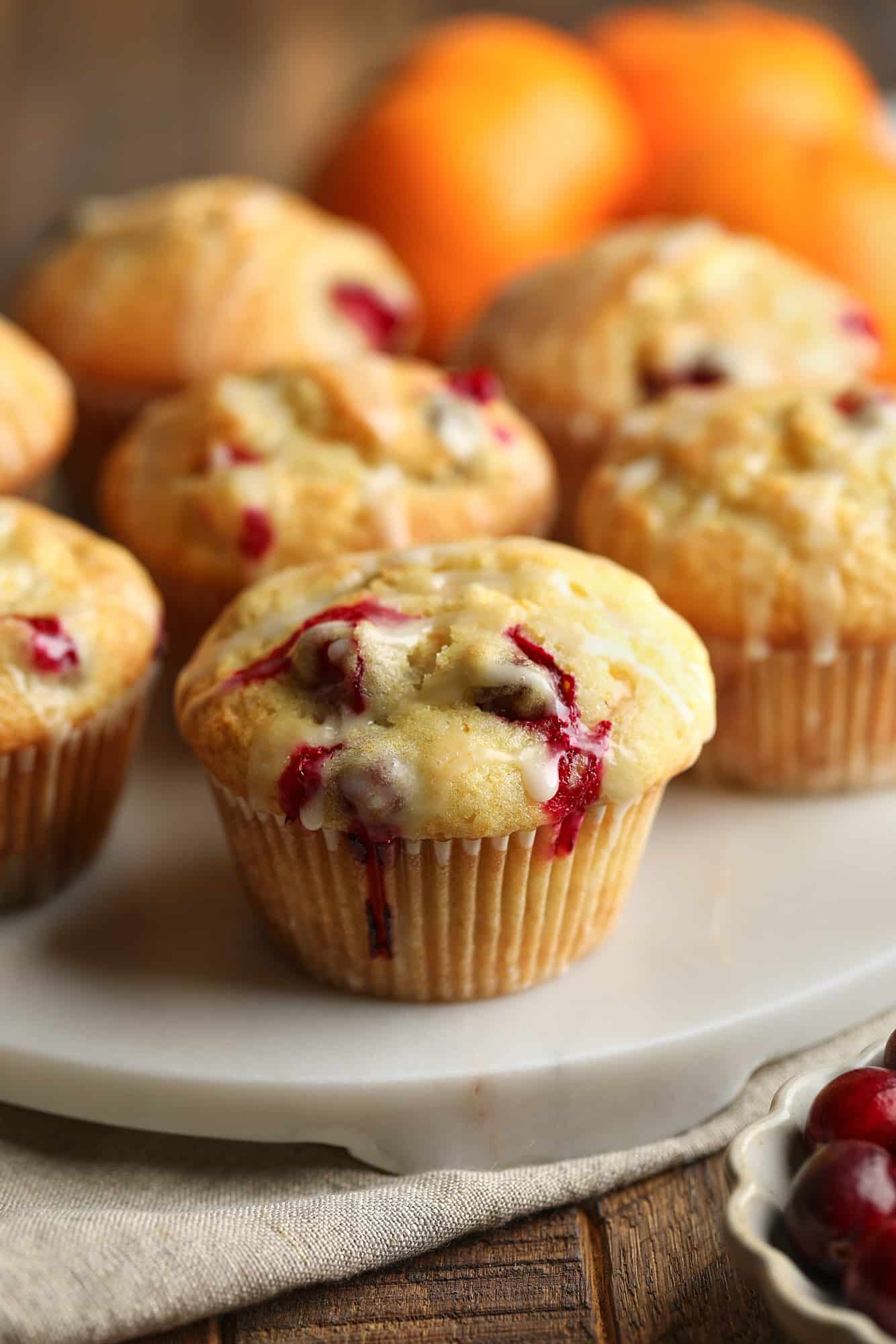 close up on a glazed cranberry orange muffin on a white plate.