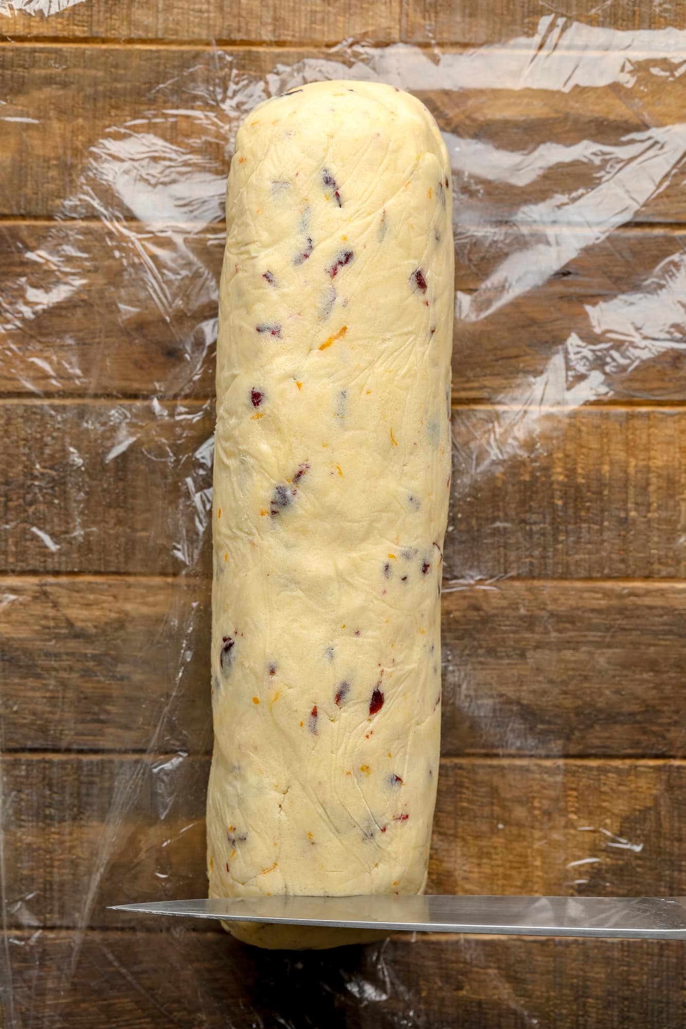 slicing a cookie dough log with a knife.