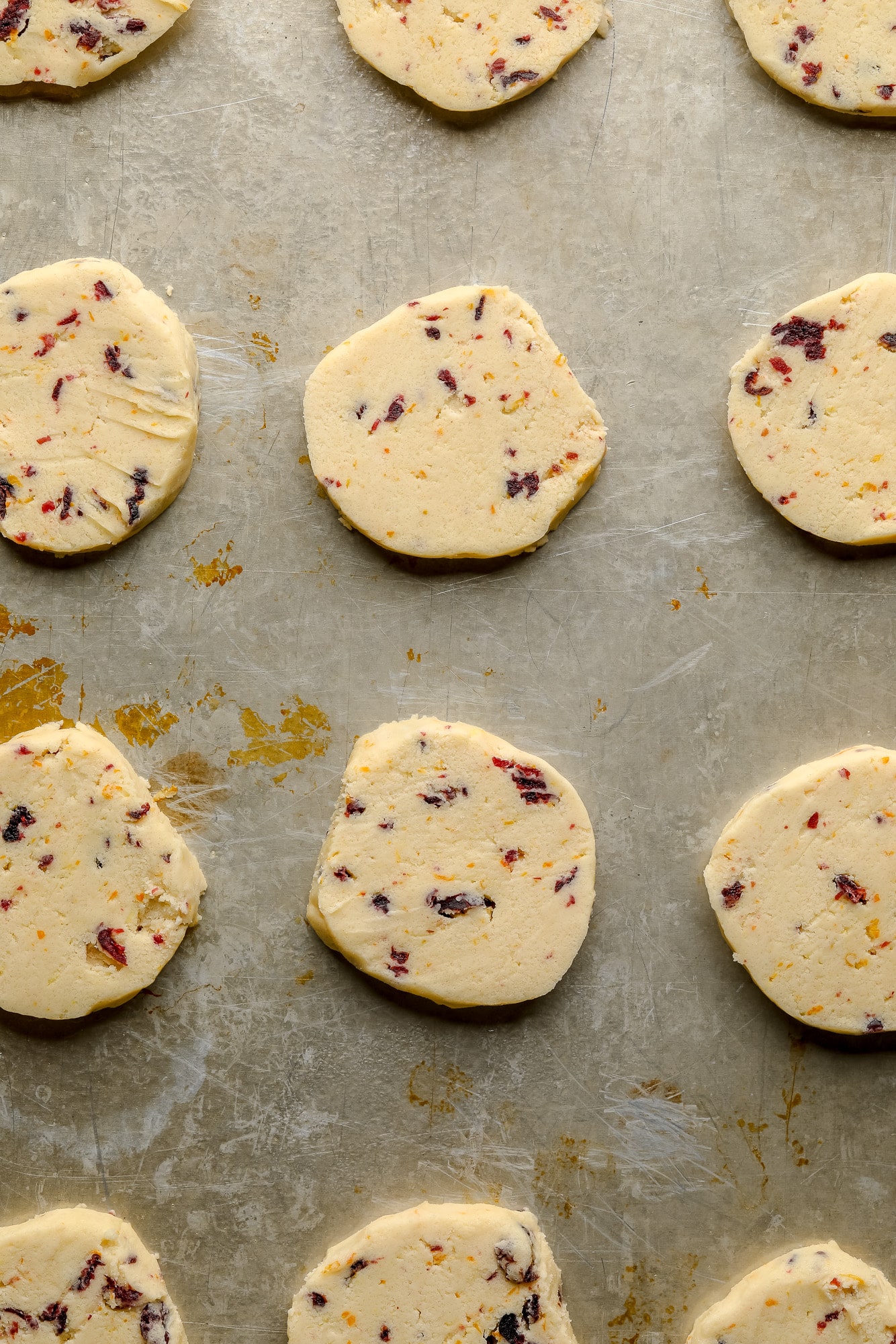 unbaked orange cranberry shortbread cookies on a metal baking sheet.