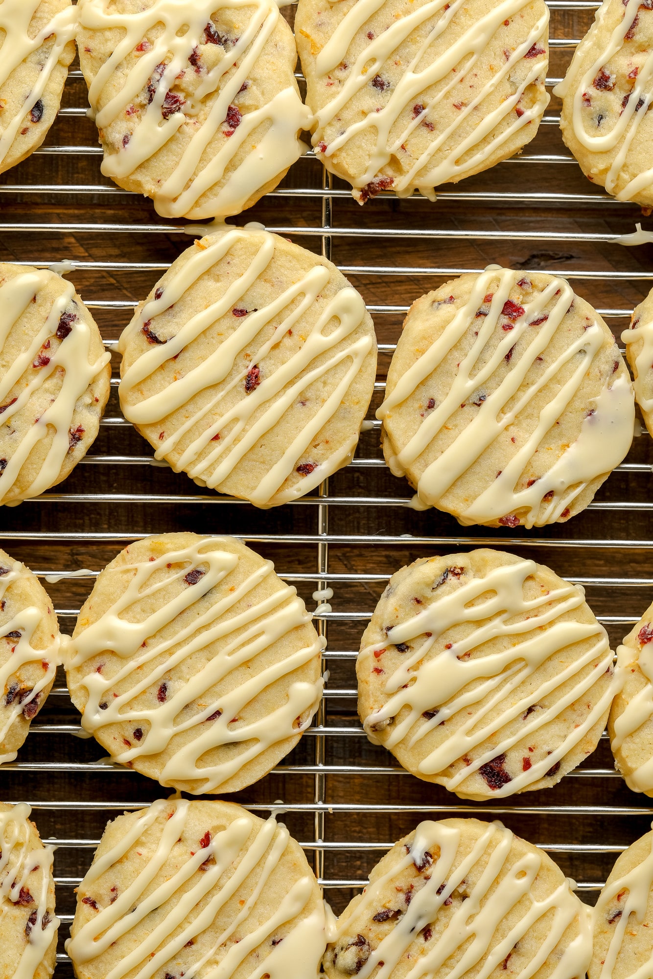 close up on Orange Cranberry Shortbread Cookies decorated with orange glaze on a wire rack.