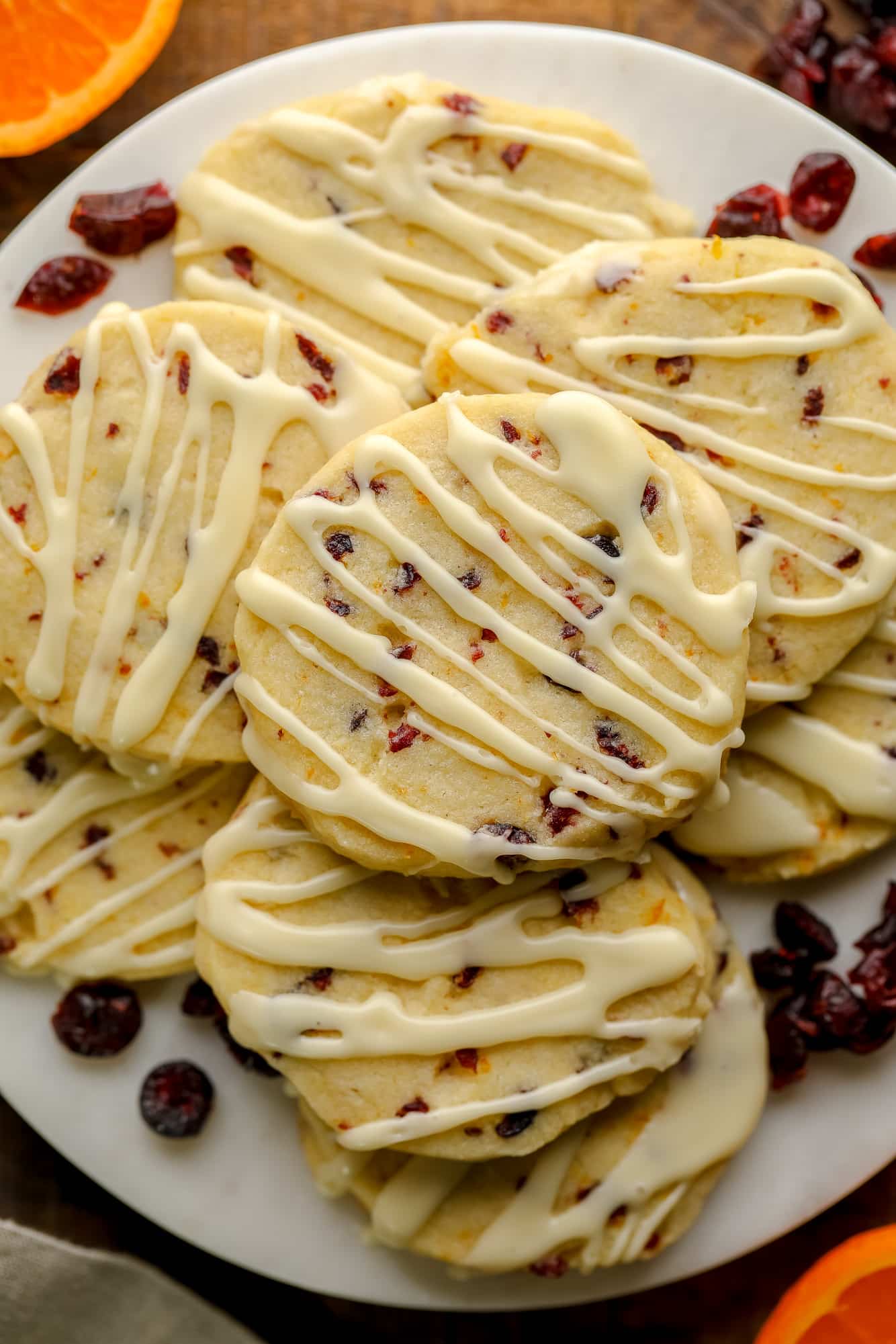 close up on a pile of Orange Cranberry Shortbread Cookies decorated with orange glaze.