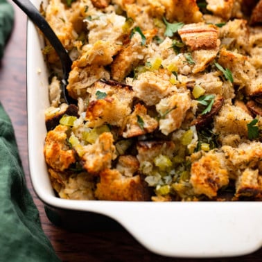 square image close up on vegan stuffing with black spoon in casserole dish