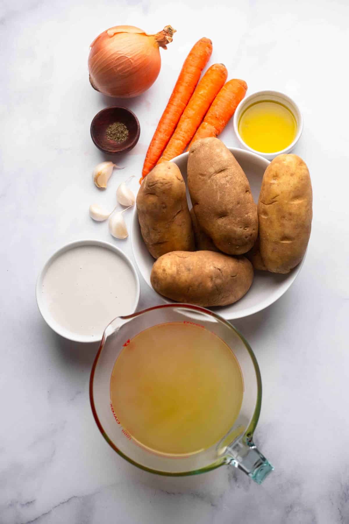 ingredients for potato soup on white marble backdrop