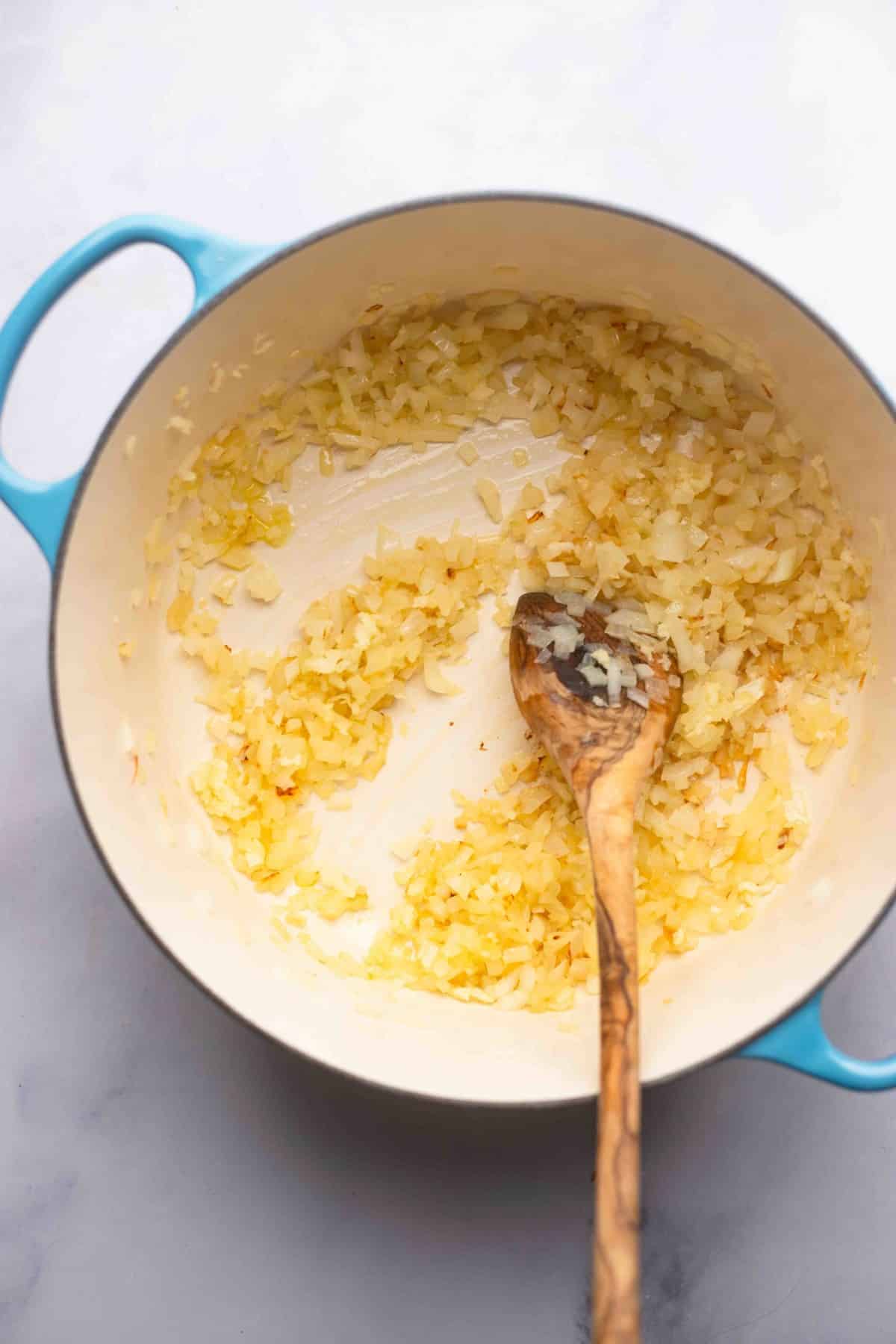 onions sauteed in a pan with wooden spoon