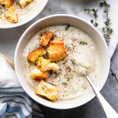 close up on a bowl of vegan cauliflower soup topped with croutons.