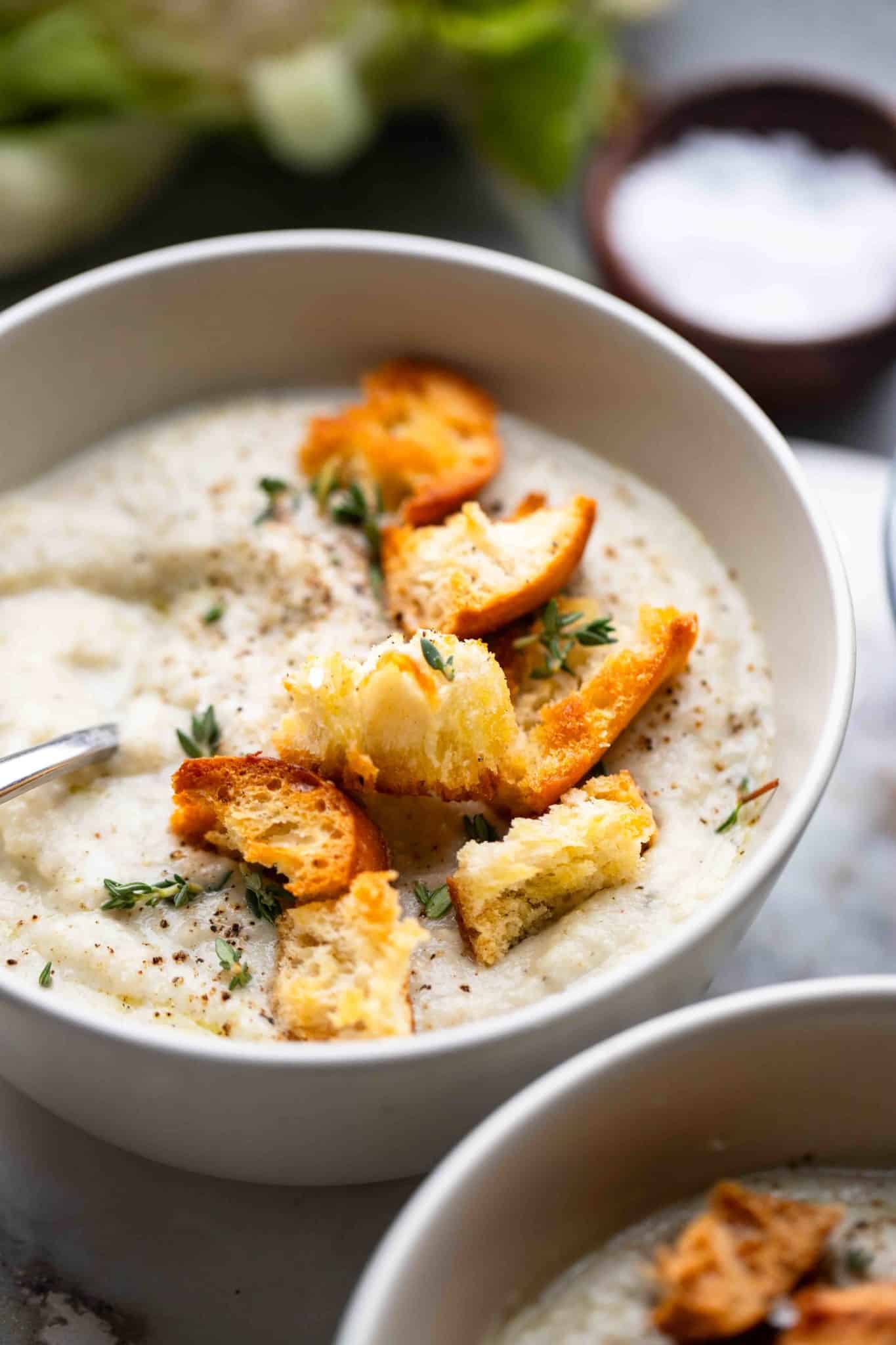 close up on a bowl of vegan cauliflower soup topped with croutons.