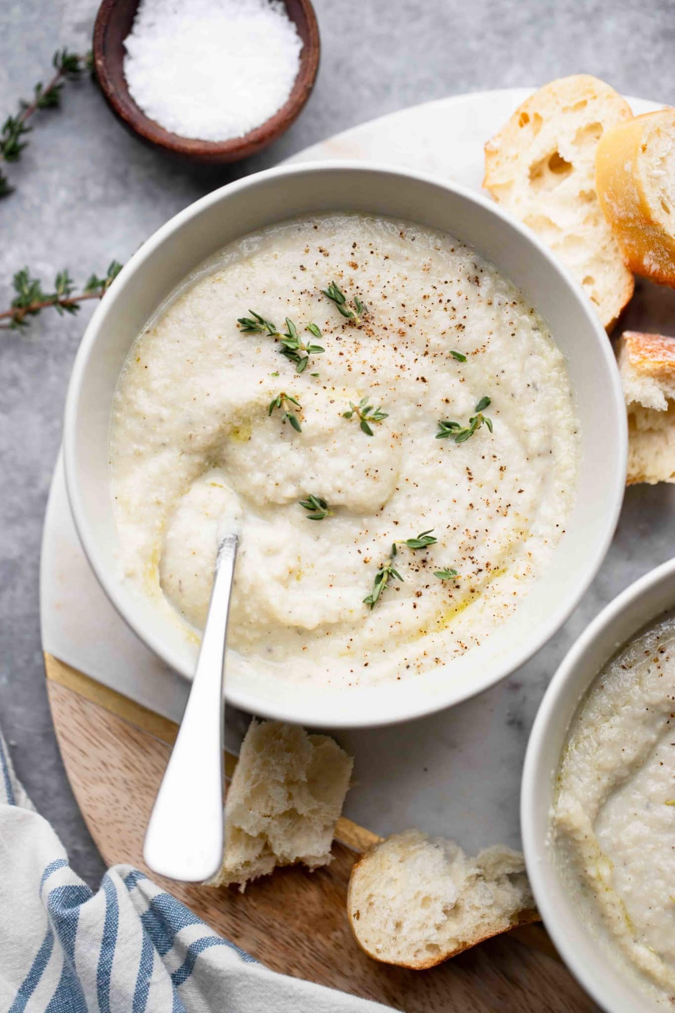 a bowl of vegan cauliflower soup topped with herbs.