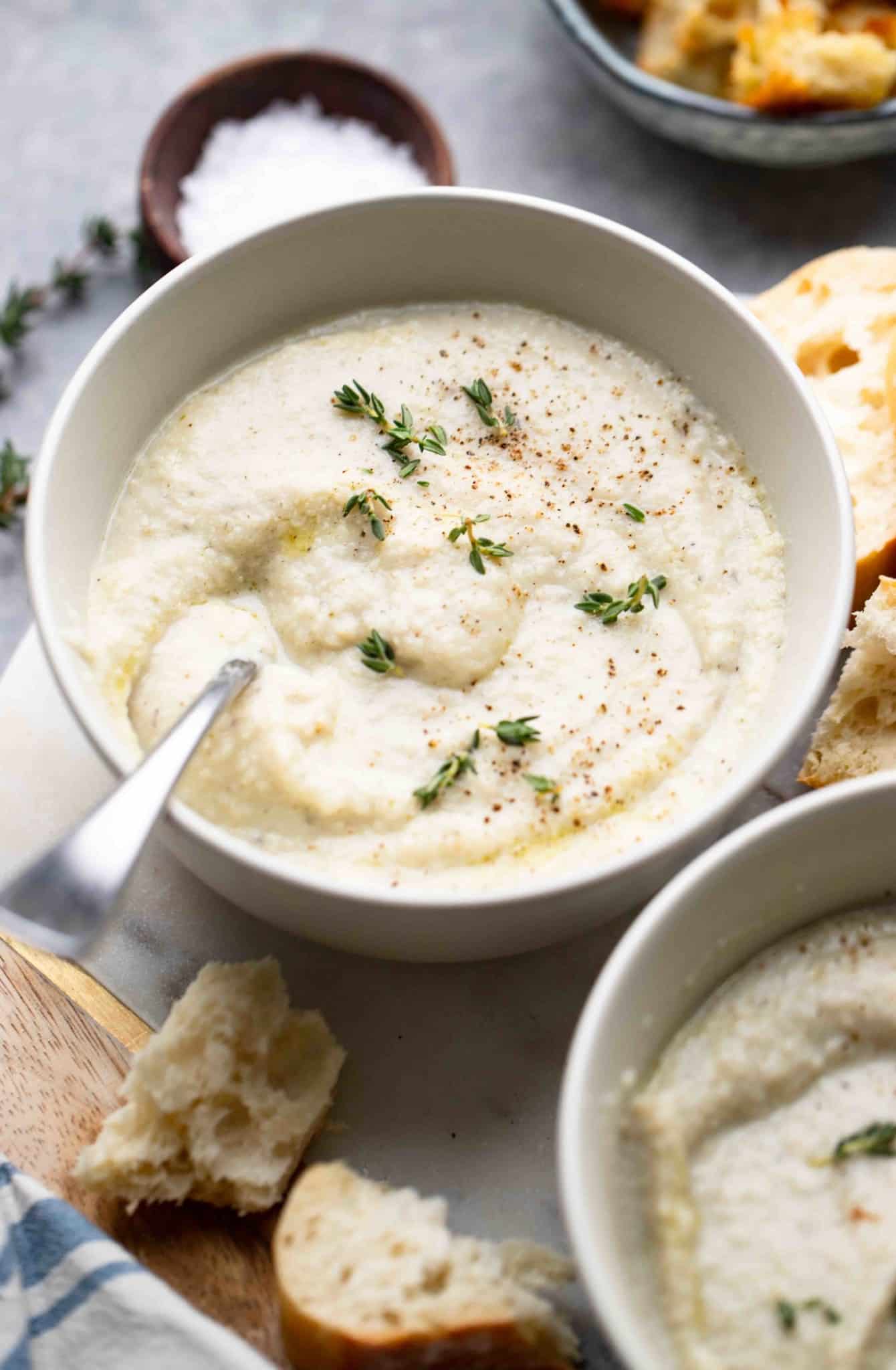 a bowl of vegan cauliflower soup topped with herbs.