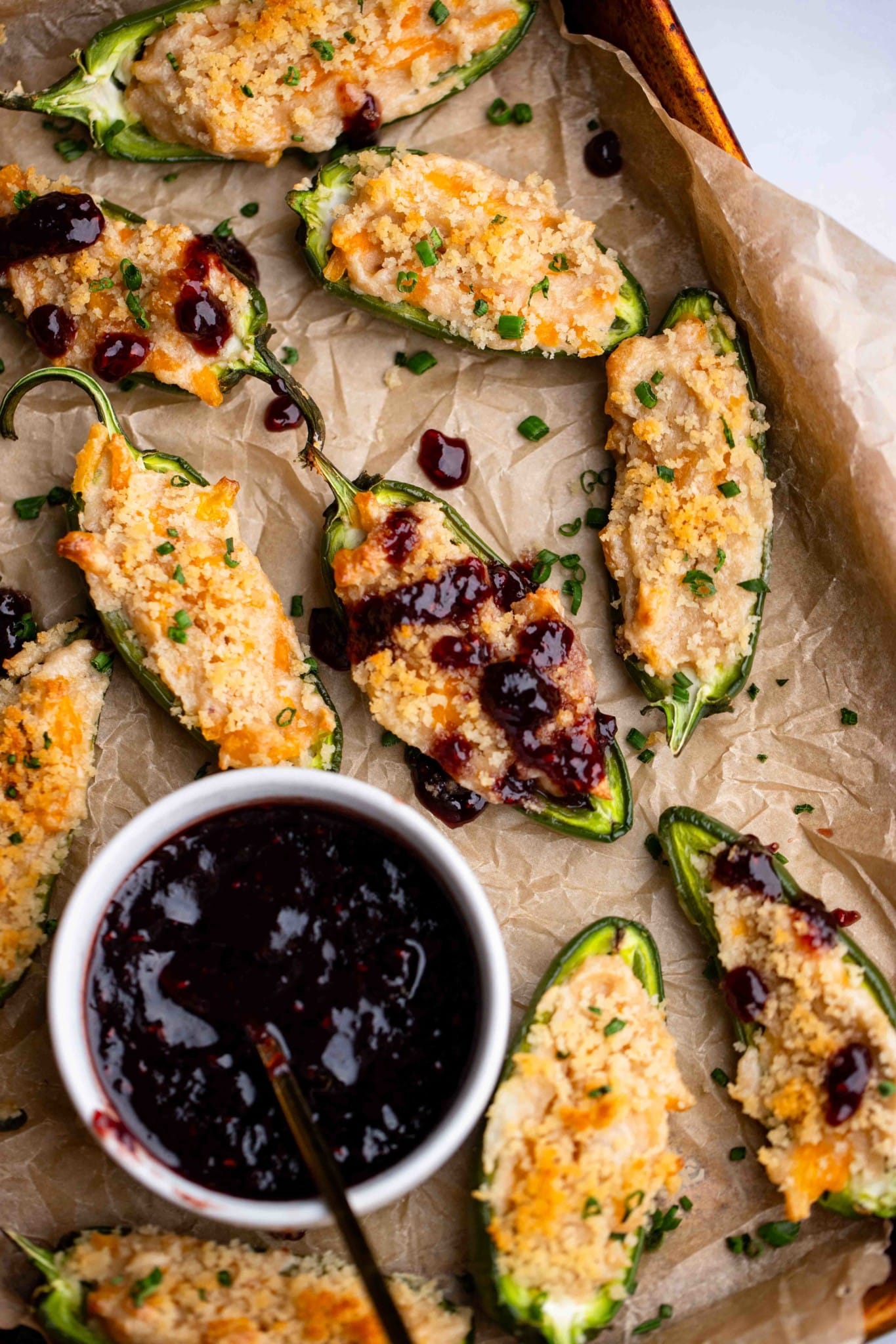 Vegan Jalapeno Poppers on a tray next to a small bowl of raspberry sauce.