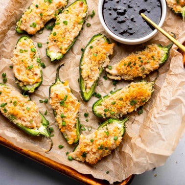 Vegan Jalapeno Poppers on a tray next to a small bowl of raspberry sauce.