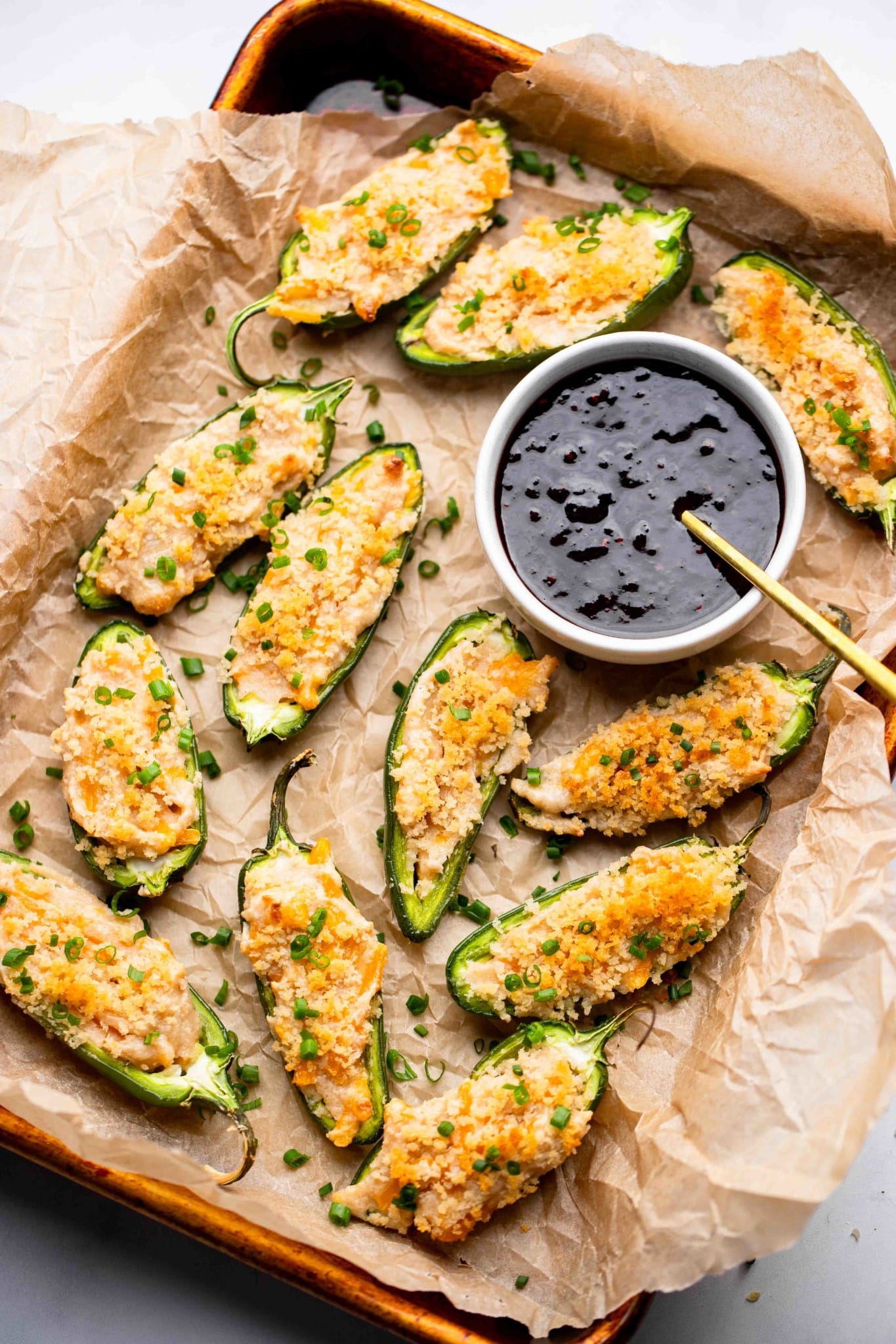 Vegan Jalapeno Poppers on a tray next to a small bowl of raspberry sauce.