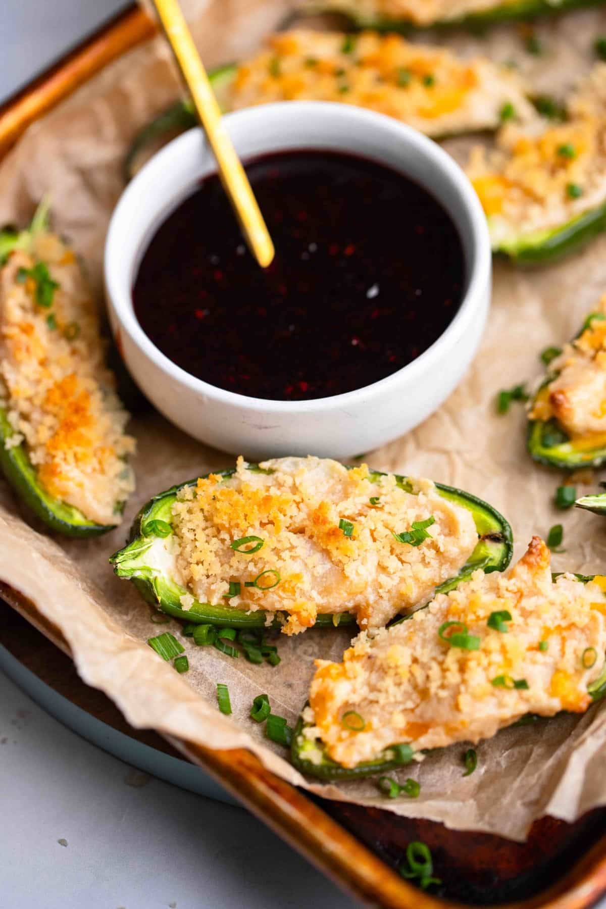 close up on Vegan Jalapeno Poppers on a tray next to a bowl of raspberry sauce.