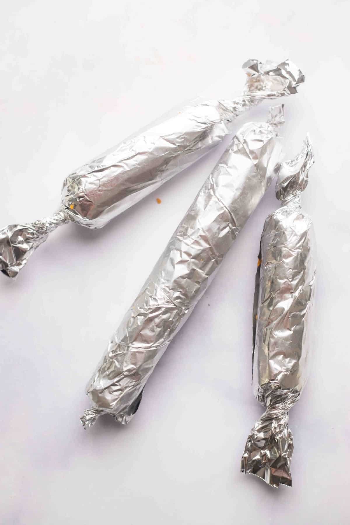 3 vegan pepperoni logs wrapped in foil.