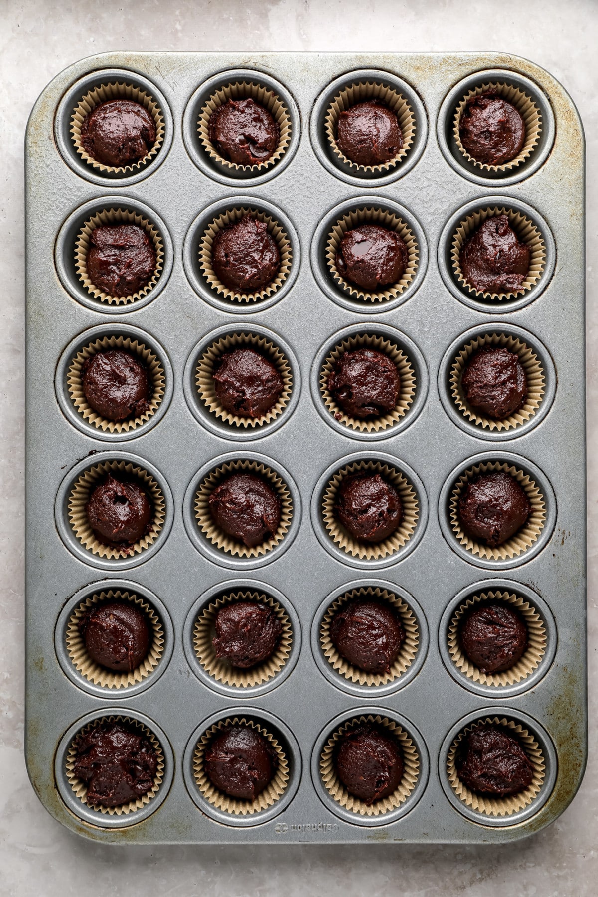 uncooked brownie batter in cups in mini muffin pan