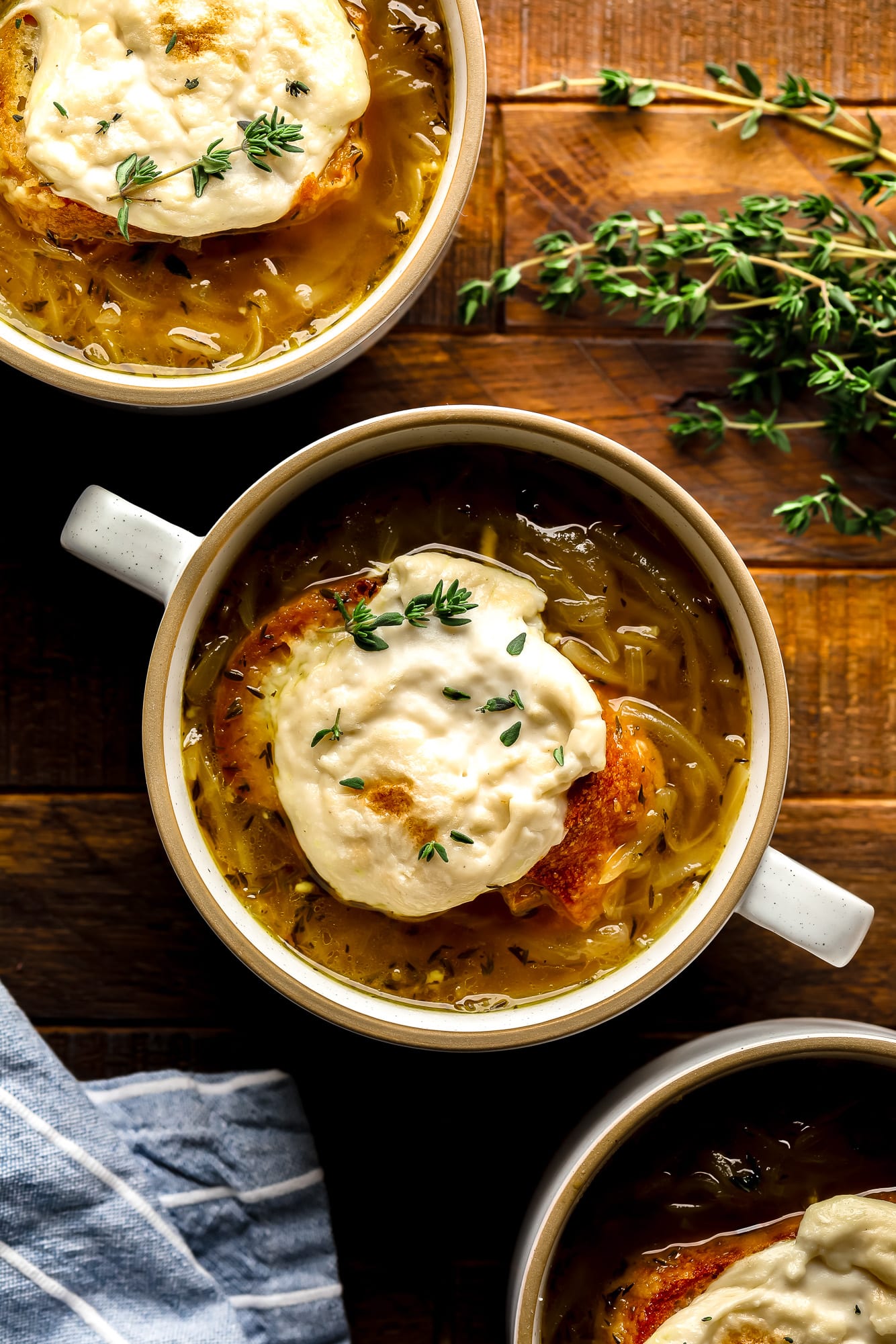 a bowl of Vegan French Onion Soup topped with toasted vegan cheesy bread.