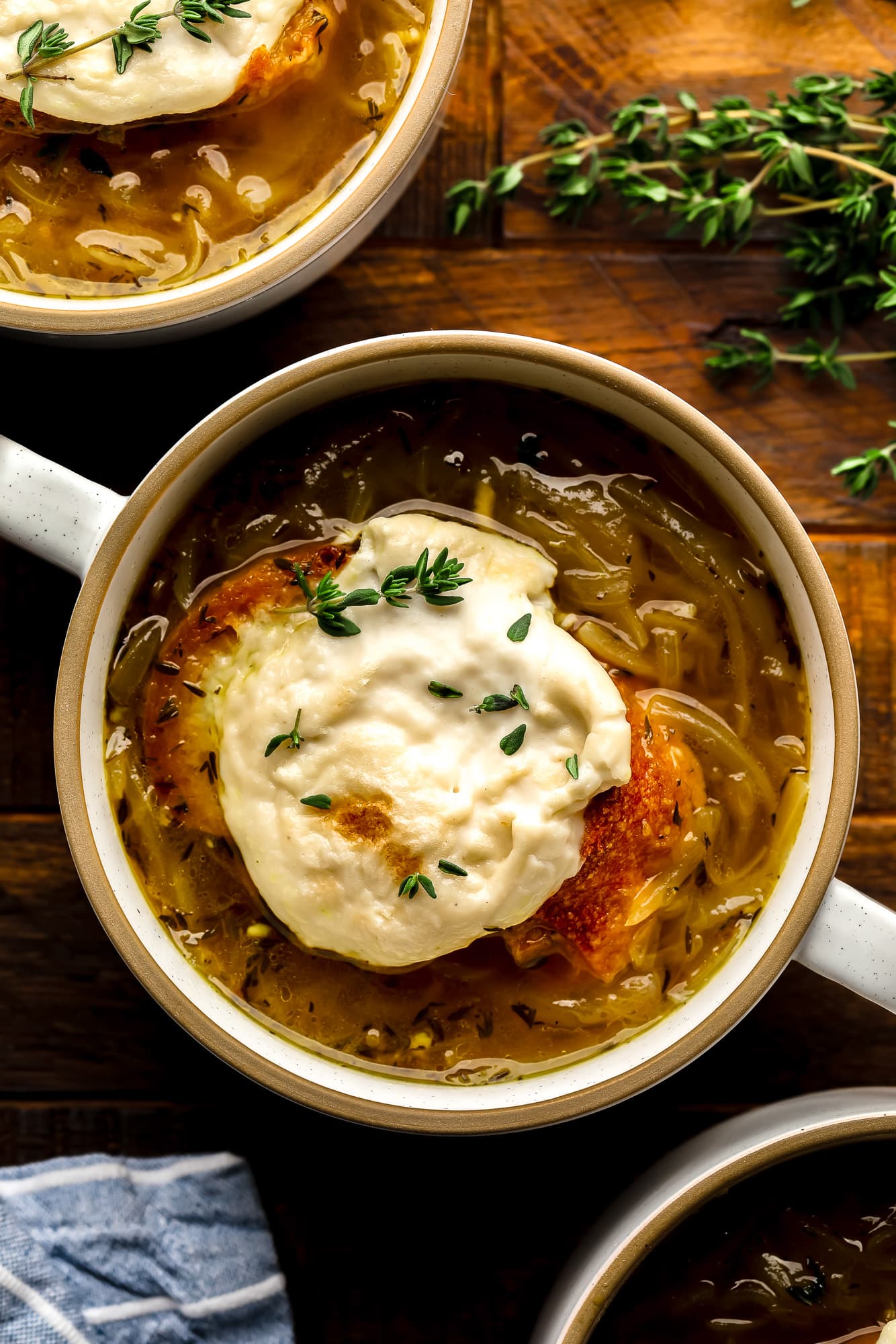 a bowl of Vegan French Onion Soup topped with toasted vegan cheesy bread.