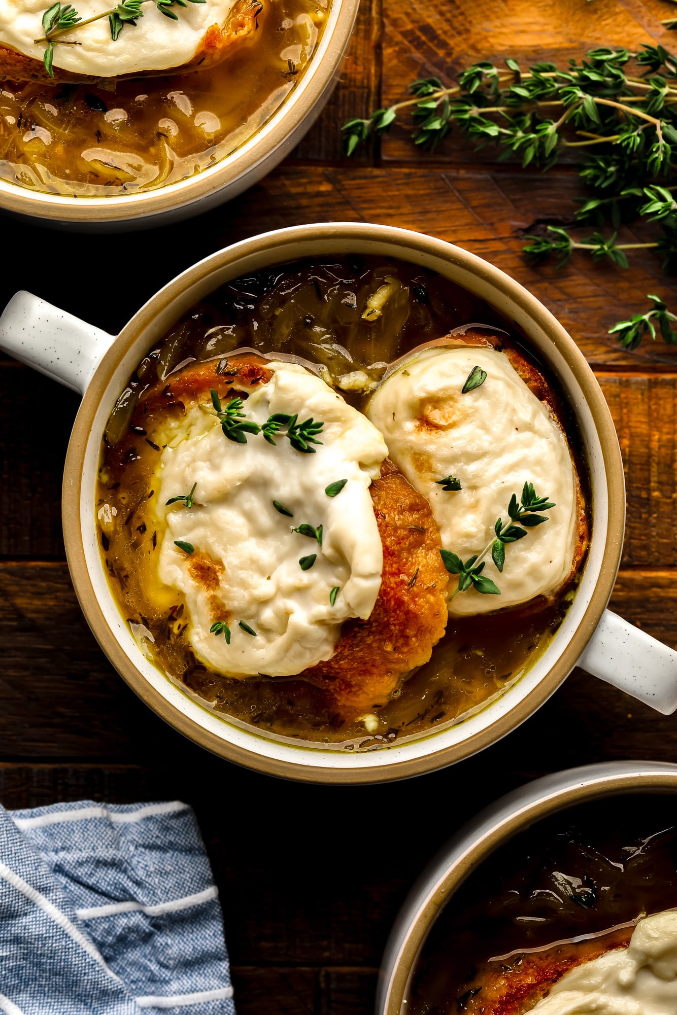 a bowl of Vegan French Onion Soup topped with toasted vegan cheesy bread.