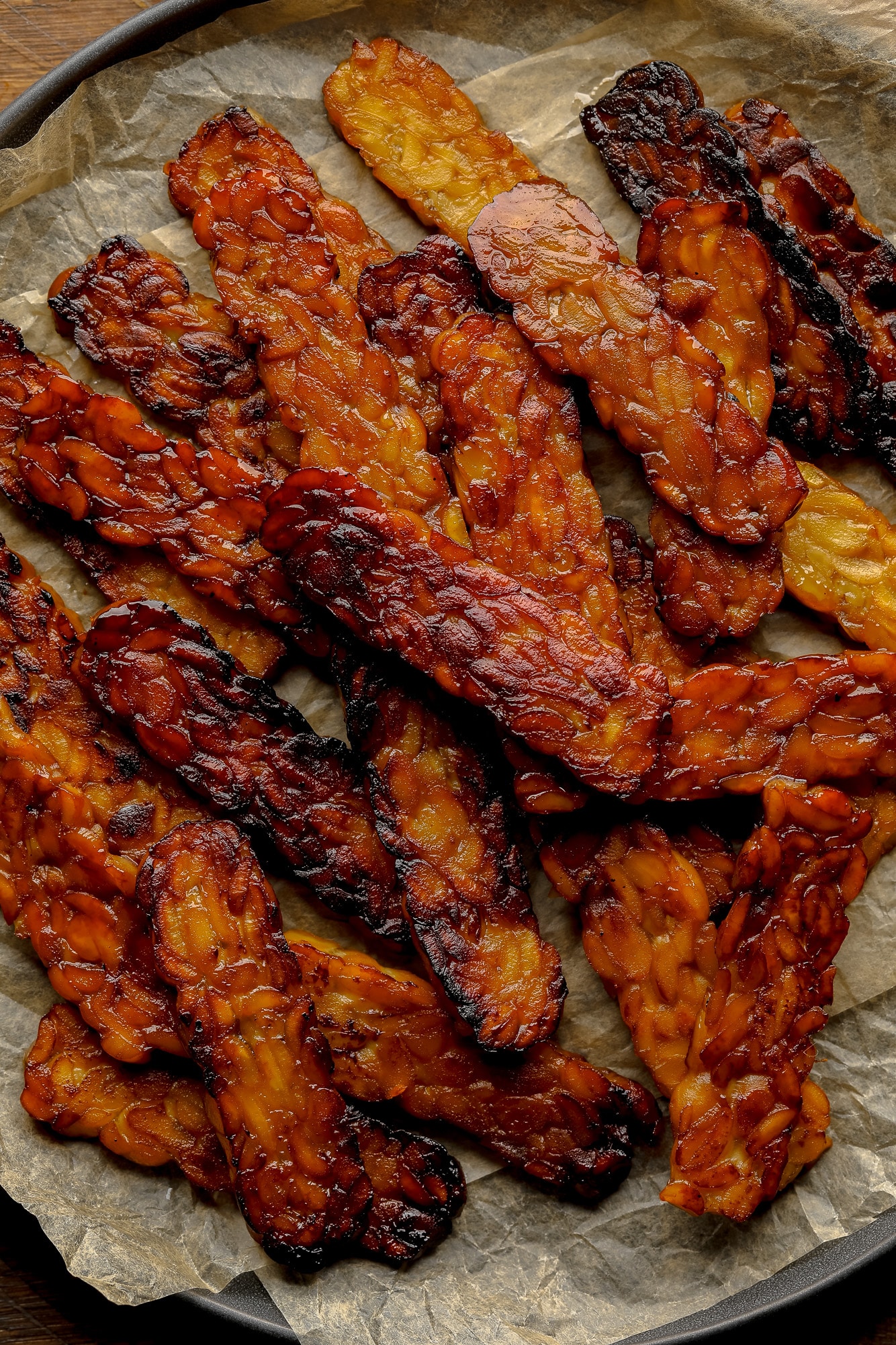 close up on a pile of pan-fried tempeh bacon slices.