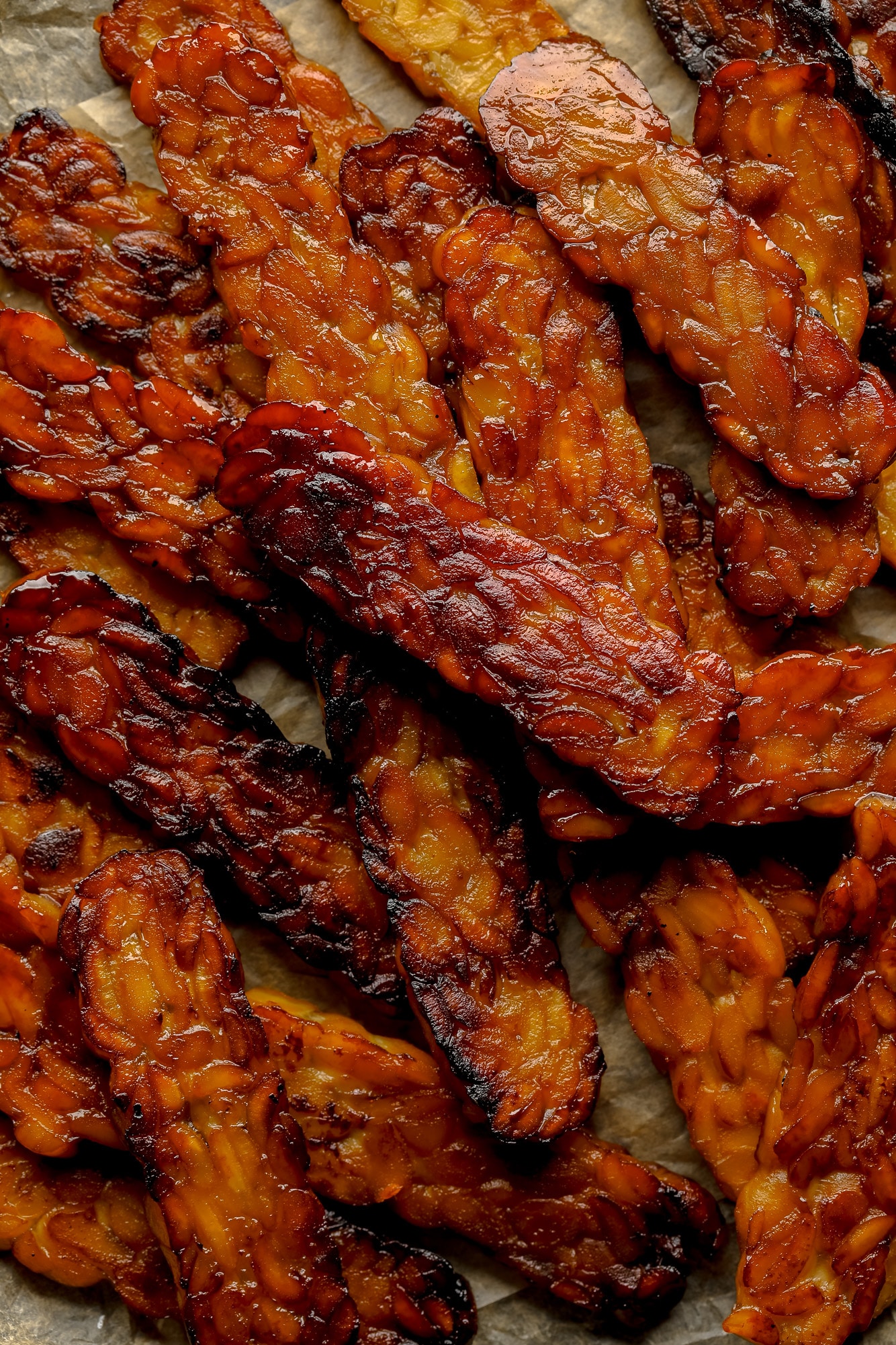 close up on a pile of pan-fried tempeh bacon slices.