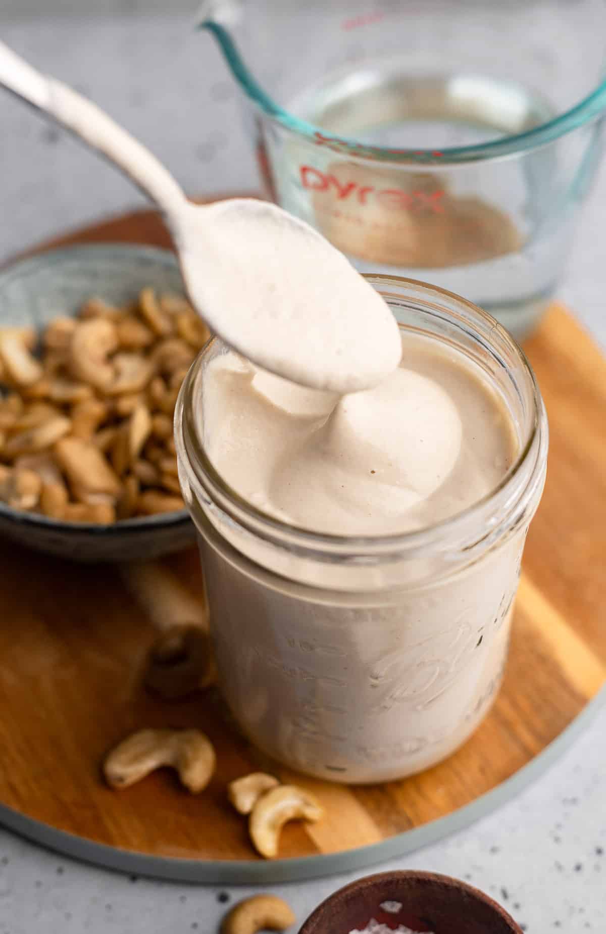 a spoon lifting out of a jar of cashew cream.