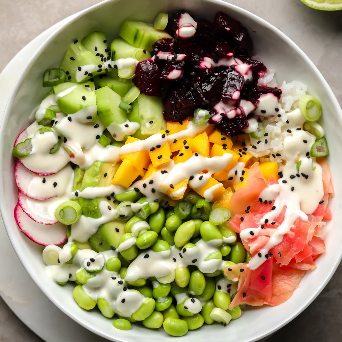 A beet poke bowl topped with marinated beets, mango, radishes, edamame, cucumber, pickled ginger, and wasabi mayo.