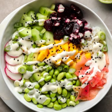 A beet poke bowl topped with marinated beets, mango, radishes, edamame, cucumber, pickled ginger, and wasabi mayo.